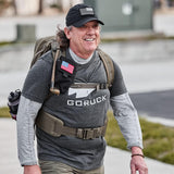 Man rucking outdoors in GORUCK Three Rules Tee, black cap, backpack, and tactical belt