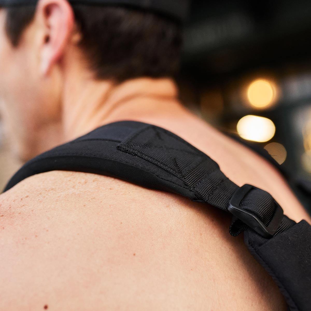 Close-up of a person wearing a black backpack strap over their bare shoulder.