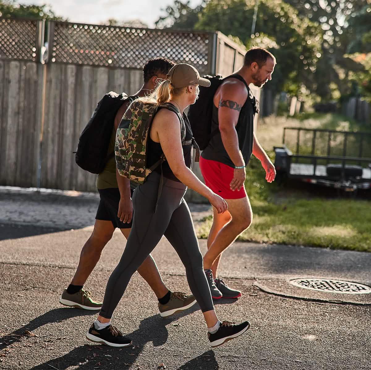 Group of people rucking outdoors with GORUCK gear and backpacks in sunlight.
