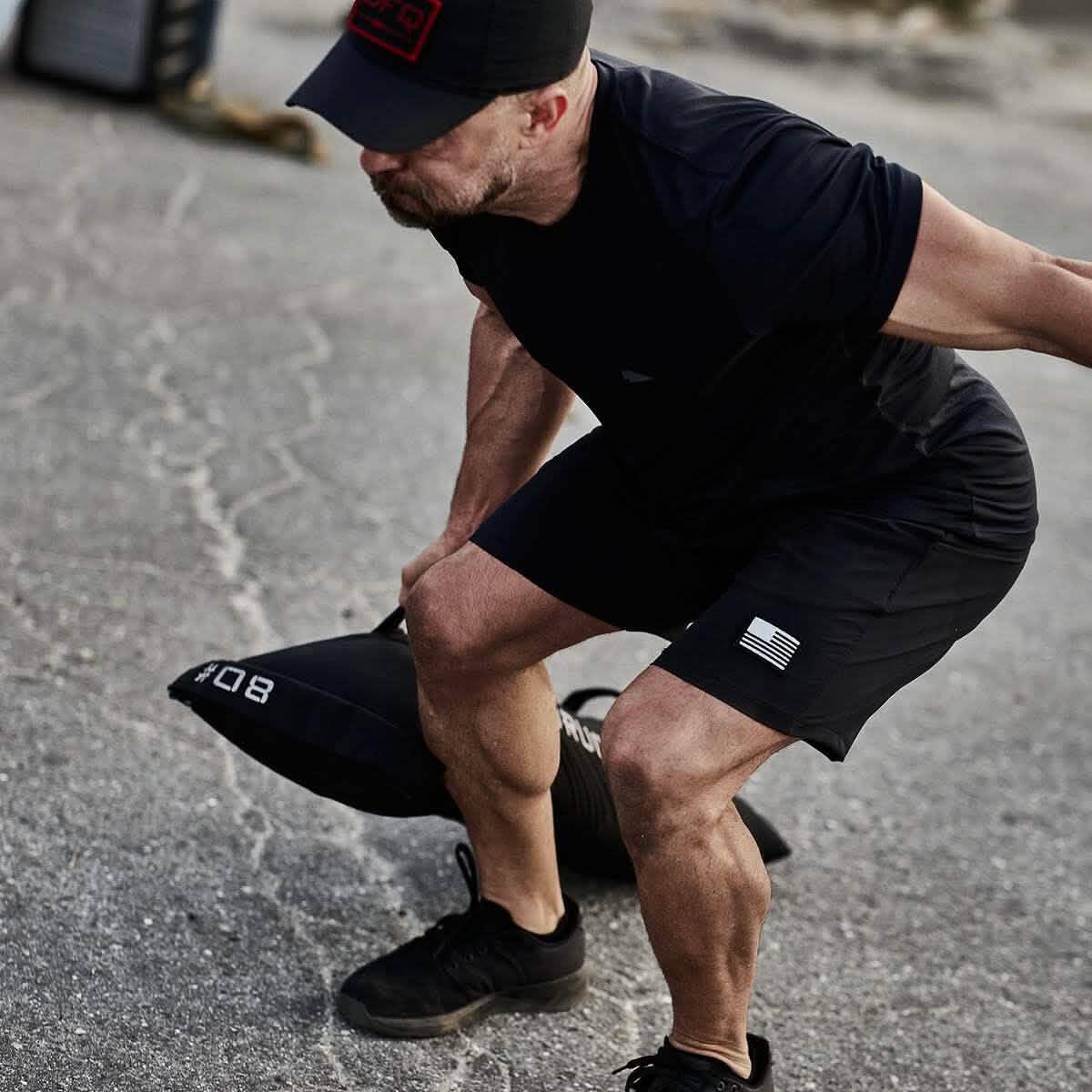 Man wearing GORUCK gear performing outdoor rucking workout with weighted sandbag