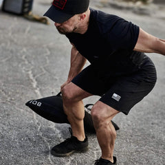 Man wearing GORUCK gear performing outdoor rucking workout with weighted sandbag