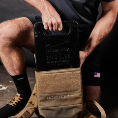 Man placing GORUCK 20LB ruck plate into tan GORUCK rucksack for rucking workout