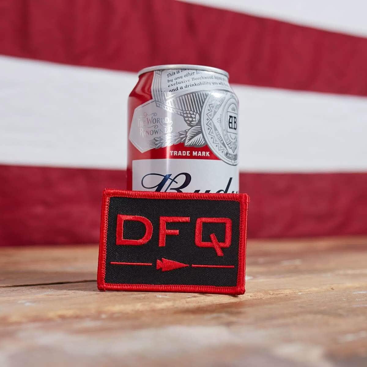 GORUCK DFQ black and red patch on wood table with beer can and American flag background