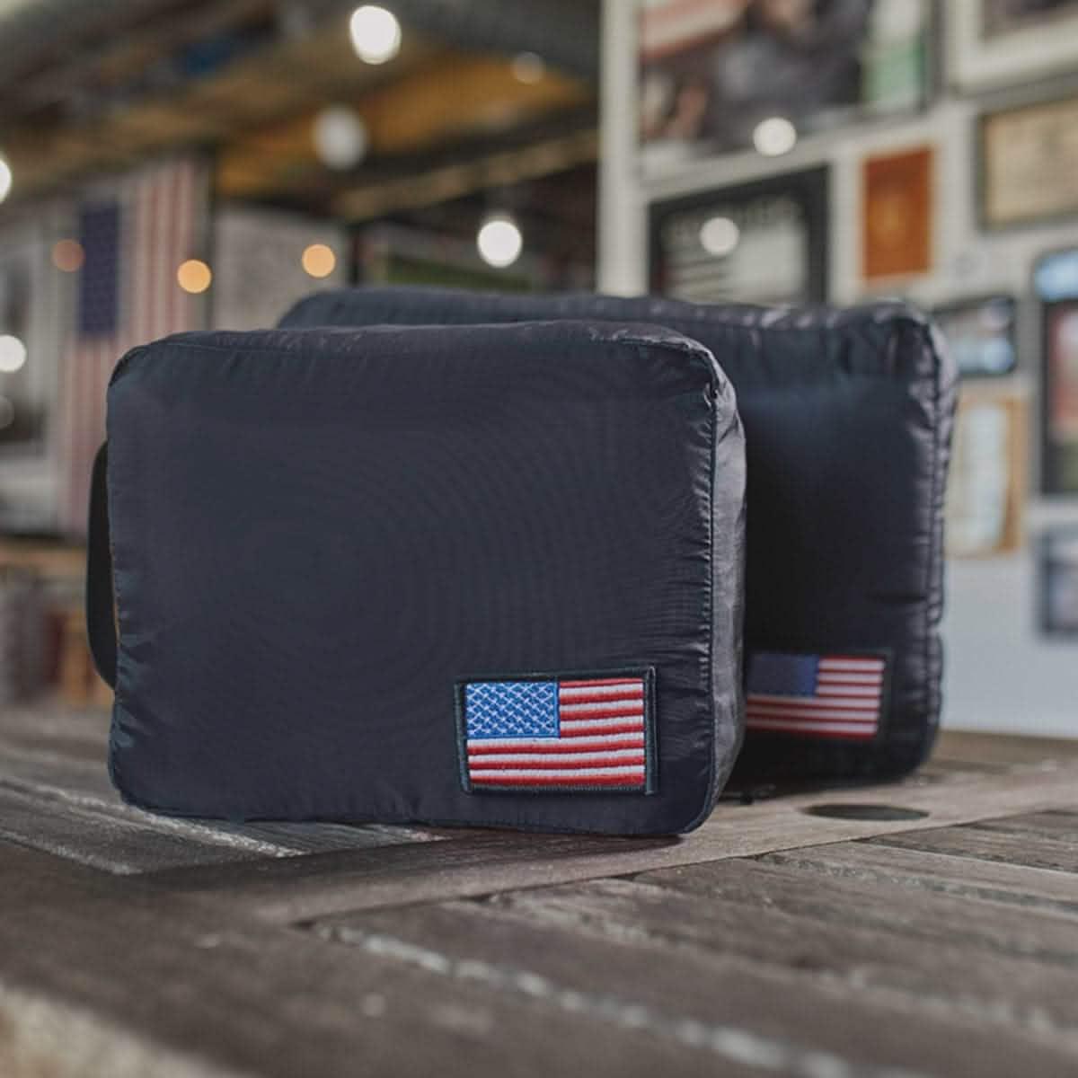 GORUCK black packing cubes with American flag patch on wooden table in rustic room