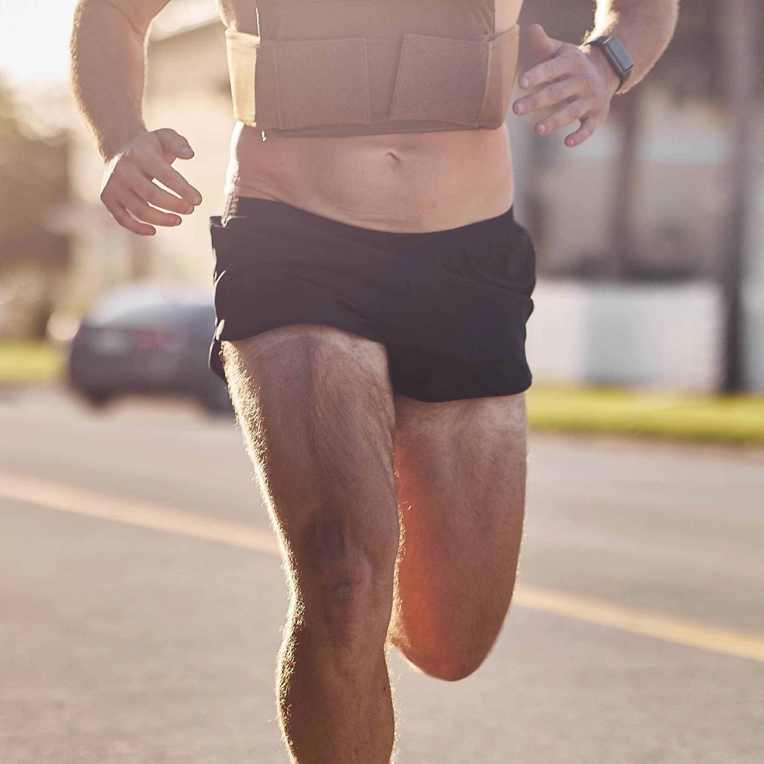Man running outdoors in GORUCK Ranger Panties shorts and weighted vest on sunny street.
