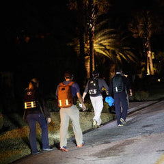Group wearing GORUCK rucksacks with reflective bands walking at night on a street