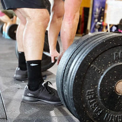 Man in GORUCK black ballistic reflective shoes deadlifting heavy barbell in gym