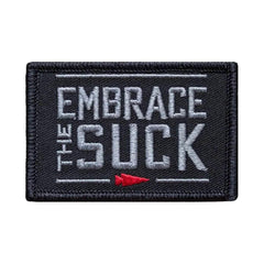 GORUCK black embroidered patch with gray 'Embrace the Suck' text and red arrow accent.