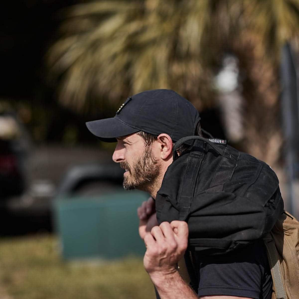 Man rucking outdoors wearing GORUCK tac hat and carrying a black weighted backpack