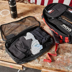 GORUCK 10L packing cube open with folded clothes beside rucksack and water bottle on wood table