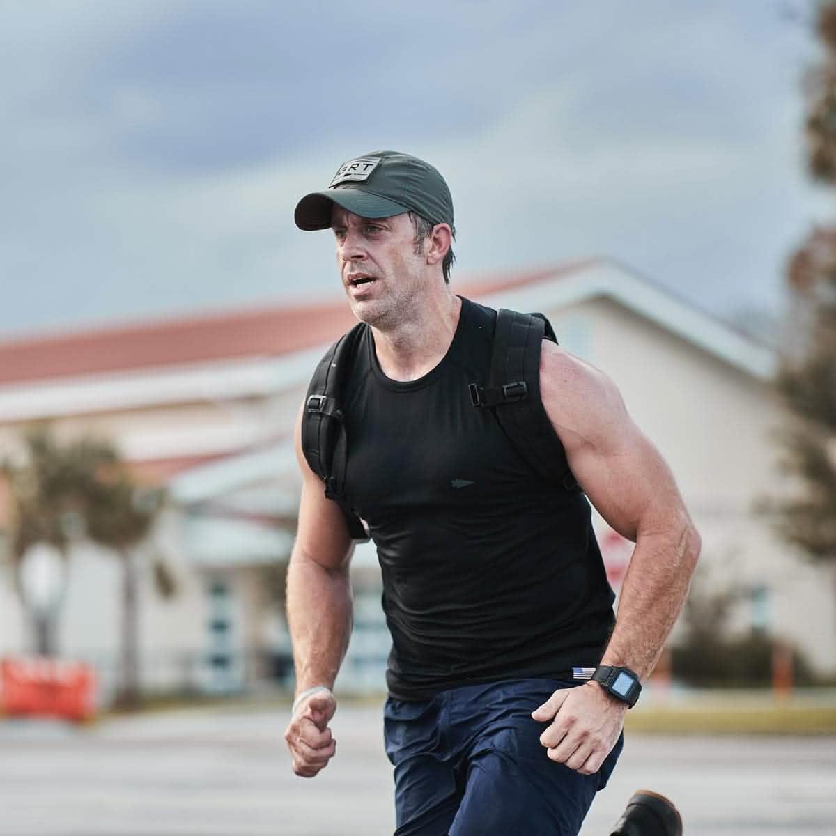 Man wearing GORUCK performance tac hat and backpack rucking outdoors in athletic gear