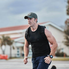 Man wearing GORUCK performance tac hat and backpack rucking outdoors in athletic gear