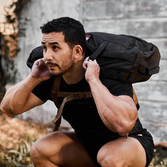 Man doing squats outdoors with GORUCK sandbag, fitness and rucking training gear