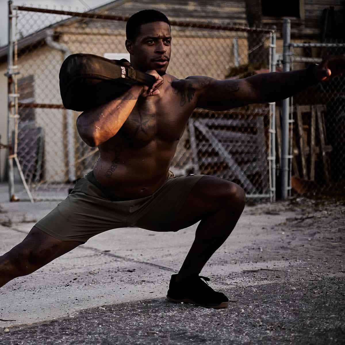 Athletic man training outdoors with GORUCK sandbag, showcasing durable fitness gear