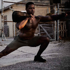 Athletic man training outdoors with GORUCK sandbag, showcasing durable fitness gear