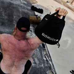 Man lifting GORUCK 44 lb sandbag outdoors, showcasing durable rucking gear